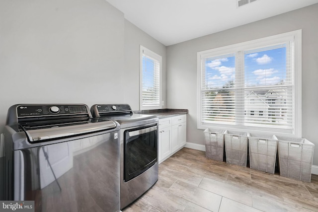 laundry area with separate washer and dryer, cabinet space, and baseboards