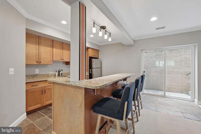 10008 Murnane St, Vienna, VA 22181 - kitchen with visible vents, freestanding refrigerator, ornamental molding, a kitchen breakfast bar, and a sink