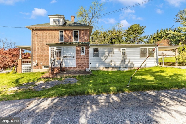 rear view of house featuring a lawn, a chimney, entry steps, and brick siding