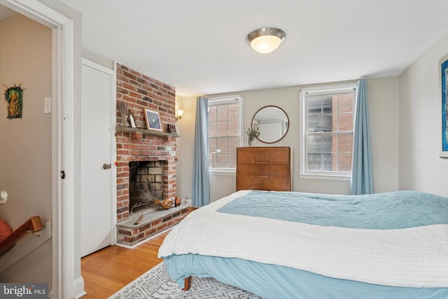 bedroom with multiple windows, wood finished floors, and a fireplace