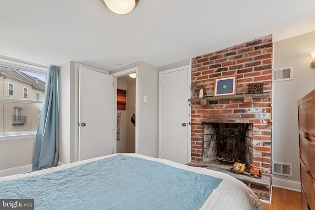 bedroom featuring baseboards, wood finished floors, and visible vents
