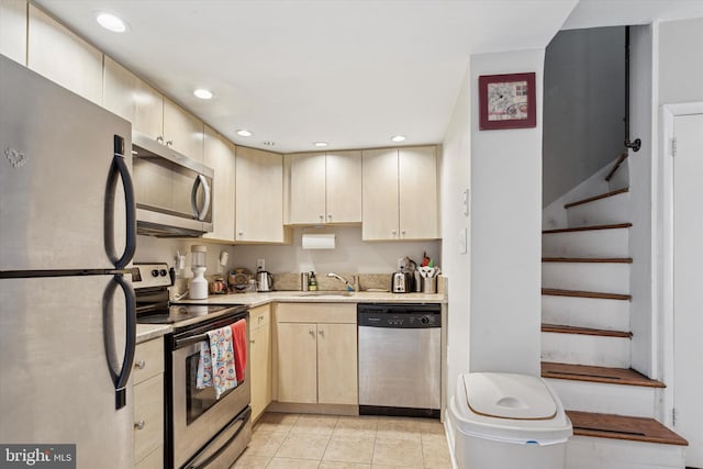 kitchen with a sink, light tile patterned flooring, light brown cabinetry, appliances with stainless steel finishes, and recessed lighting
