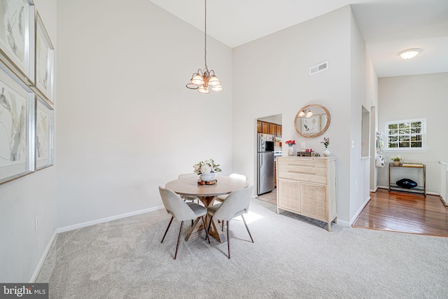 8818 Tanglewood Ln, Manassas, VA 20110 - dining area featuring light colored carpet, a notable chandelier, visible vents, and high vaulted ceiling