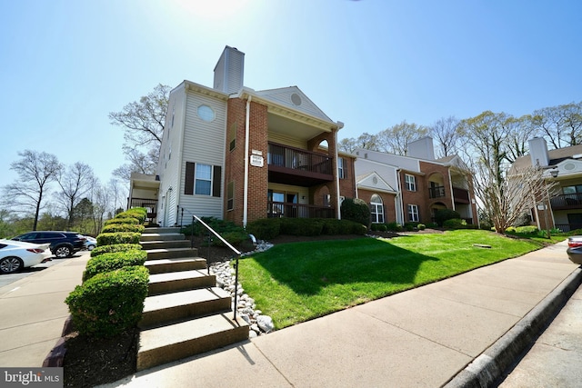 8818 Tanglewood Ln, Manassas, VA 20110 - view of front of house featuring a front lawn, brick siding, a chimney, and uncovered parking