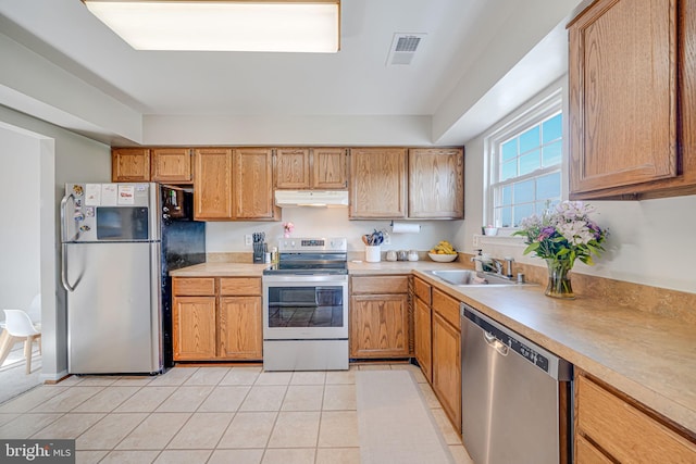 8818 Tanglewood Ln, Manassas, VA 20110 - kitchen featuring under cabinet range hood, stainless steel appliances, light countertops, light tile patterned floors, and a sink
