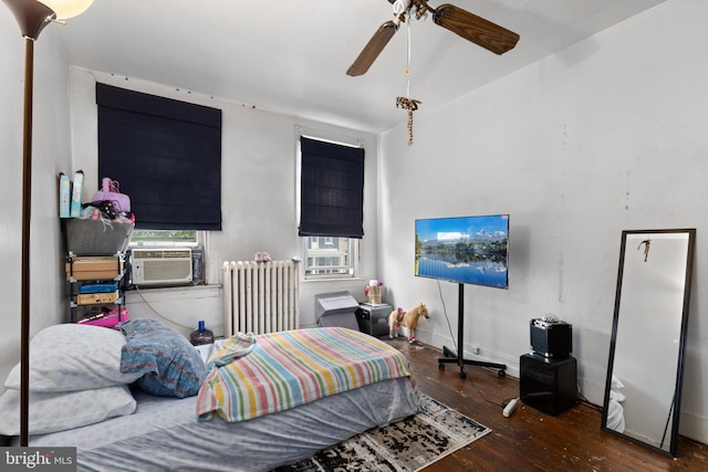 bedroom featuring radiator heating unit, cooling unit, wood-type flooring, ceiling fan, and baseboards