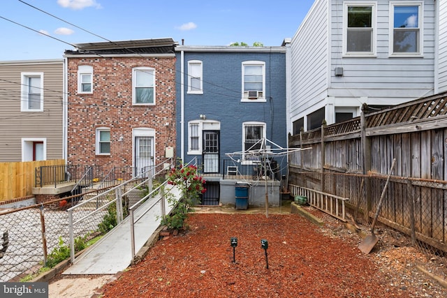 rear view of property with a fenced backyard, brick siding, and cooling unit