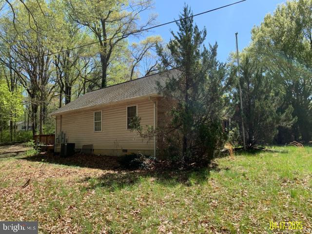 view of side of home featuring a lawn, central AC unit, and crawl space
