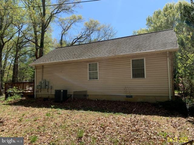 view of side of home with a shingled roof and cooling unit