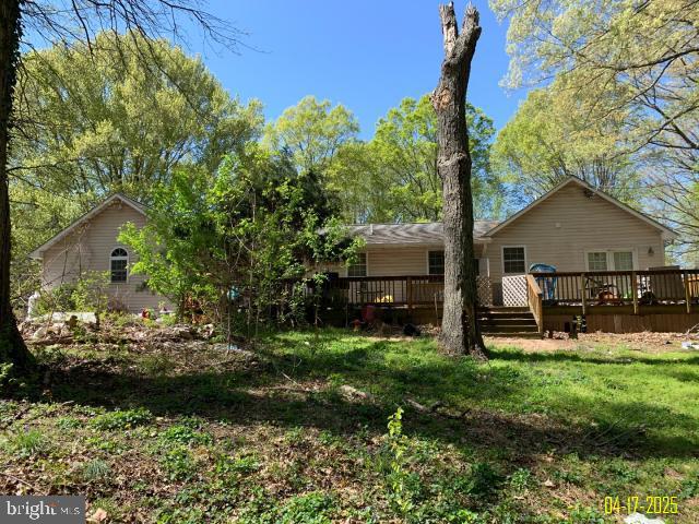 rear view of house with a wooden deck and a yard