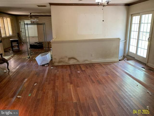 interior space featuring baseboards, a ceiling fan, wood finished floors, and crown molding