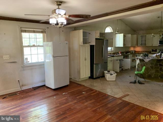 kitchen featuring stainless steel appliances, dark countertops, a ceiling fan, a sink, and light wood-style floors