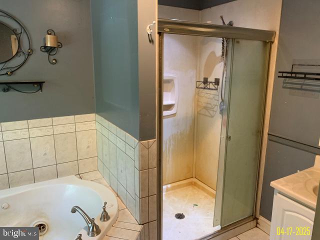 bathroom featuring vanity, a whirlpool tub, and a stall shower