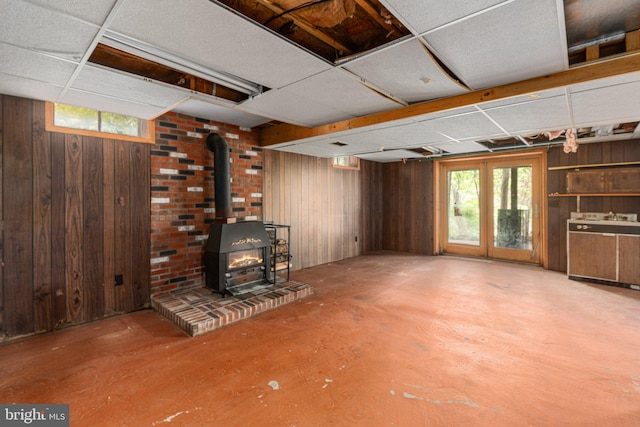 below grade area featuring a wood stove, wood walls, and a healthy amount of sunlight