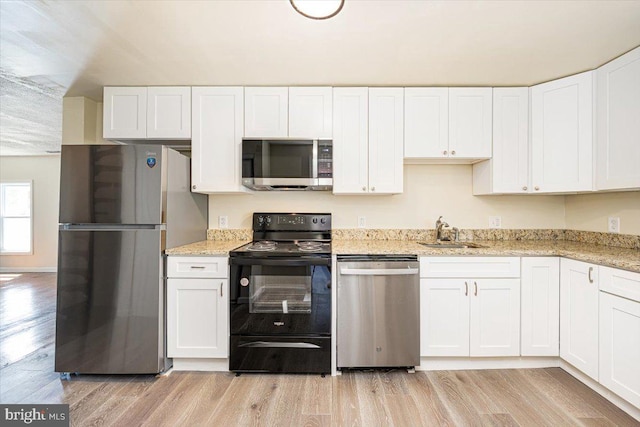 kitchen with light wood-type flooring, stainless steel appliances, white cabinets, and a sink