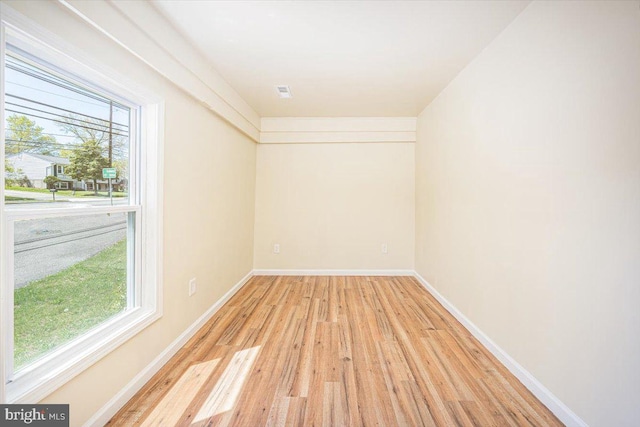 empty room featuring visible vents, light wood finished floors, and baseboards