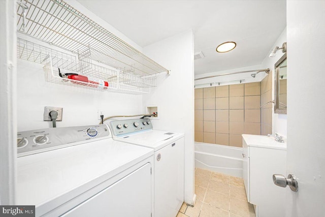 laundry room featuring light tile patterned floors, washing machine and clothes dryer, laundry area, and a sink