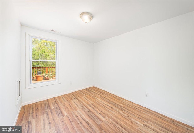 empty room with visible vents, light wood finished floors, and baseboards