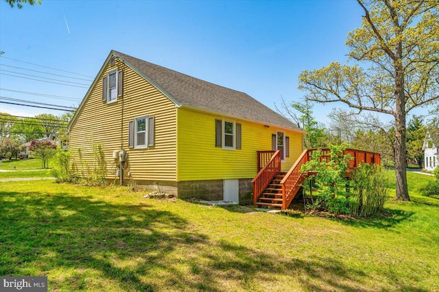 exterior space with roof with shingles, a wooden deck, stairs, and a lawn