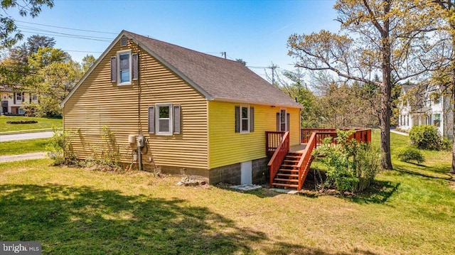 exterior space featuring a deck, a yard, a shingled roof, and stairs