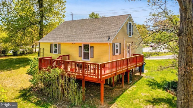 rear view of property featuring a deck, central AC, a yard, and roof with shingles