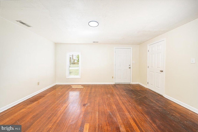 empty room with baseboards, visible vents, and wood finished floors