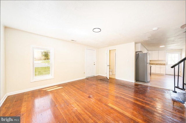 unfurnished living room featuring baseboards and hardwood / wood-style flooring