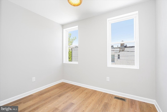 empty room featuring visible vents, light wood-style floors, and baseboards