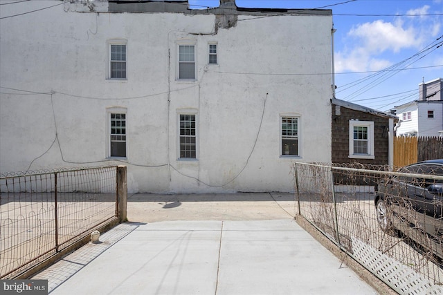 view of side of home with fence, stucco siding, and a patio area