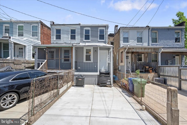 view of property with a porch, a fenced front yard, and central AC