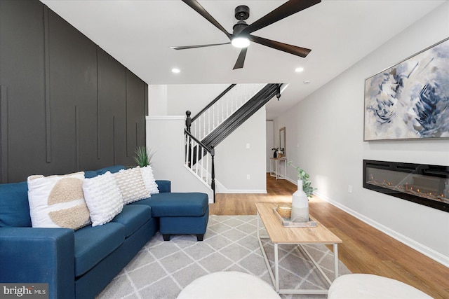 living area featuring stairs, baseboards, ceiling fan, light wood-type flooring, and recessed lighting