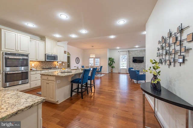 24129 Statesboro Pl, Ashburn, VA 20148 - kitchen featuring stainless steel appliances, a breakfast bar, wood finished floors, and open floor plan
