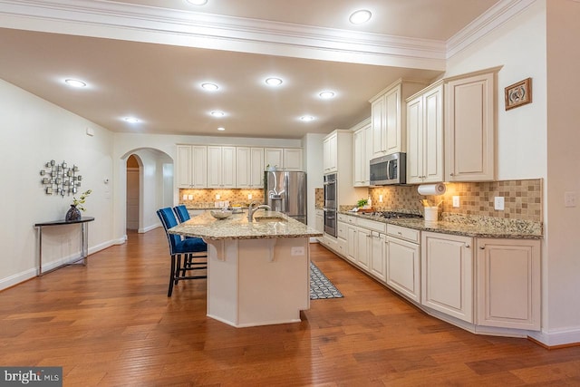24129 Statesboro Pl, Ashburn, VA 20148 - kitchen with stainless steel appliances, backsplash, a sink, arched walkways, and a breakfast bar area