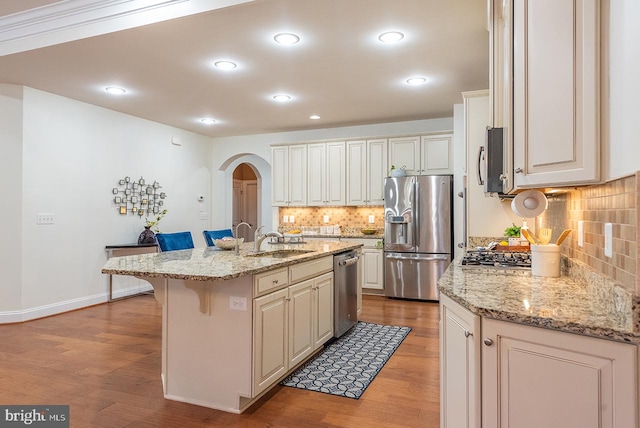 24129 Statesboro Pl, Ashburn, VA 20148 - kitchen featuring backsplash, a sink, arched walkways, light wood-style flooring, and appliances with stainless steel finishes