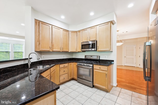 kitchen with appliances with stainless steel finishes, a sink, and light brown cabinets