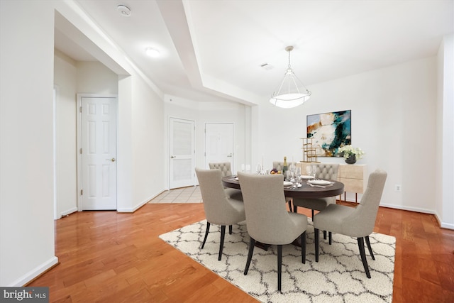dining area with baseboards, light wood finished floors, and visible vents