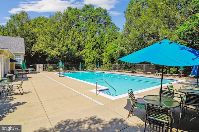 community pool with a patio and fence