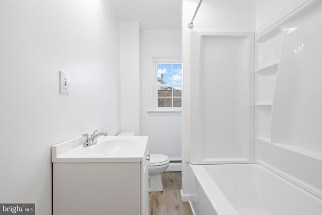 bathroom with wood finished floors, toilet, vanity,  shower combination, and a baseboard radiator