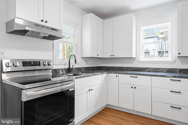 kitchen with stainless steel range with electric cooktop, under cabinet range hood, a sink, and white cabinetry