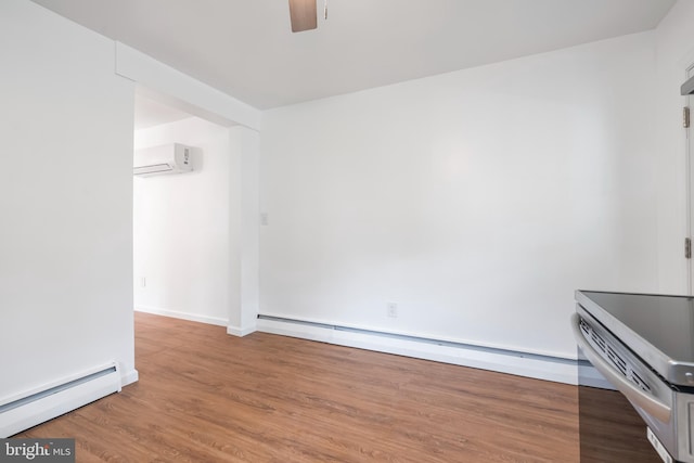 spare room featuring a baseboard radiator, a ceiling fan, wood finished floors, and a wall unit AC