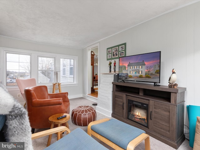 carpeted living area with baseboards, a glass covered fireplace, a textured ceiling, and ornamental molding