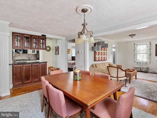 dining room featuring hardwood / wood-style flooring, crown molding, and a textured ceiling