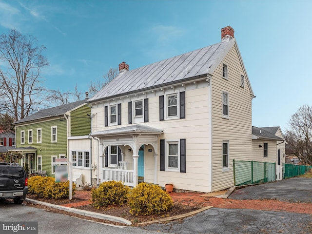 view of front of property with fence, a chimney, and covered porch