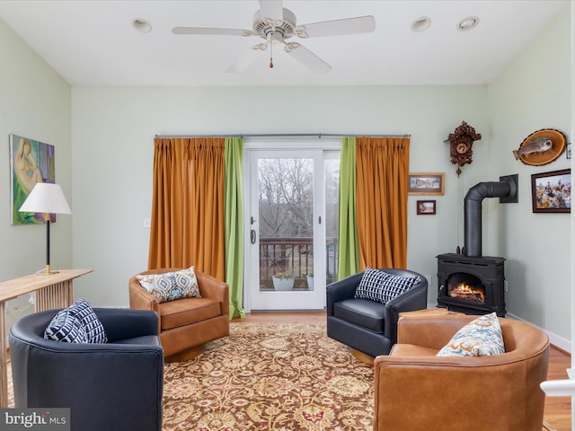 living room with a ceiling fan, a wood stove, wood finished floors, and recessed lighting