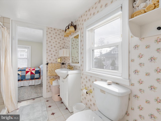 bathroom with wallpapered walls, tile patterned floors, toilet, vanity, and ensuite bath