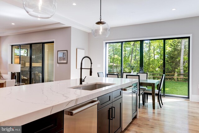 kitchen featuring a sink, recessed lighting, pendant lighting, light stone counters, and dishwasher