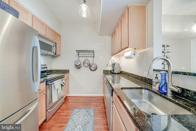 880 N Pollard St Unit 1021, Arlington, VA 22203 - kitchen featuring appliances with stainless steel finishes, a sink, light wood-style floors, light brown cabinets, and dark stone countertops