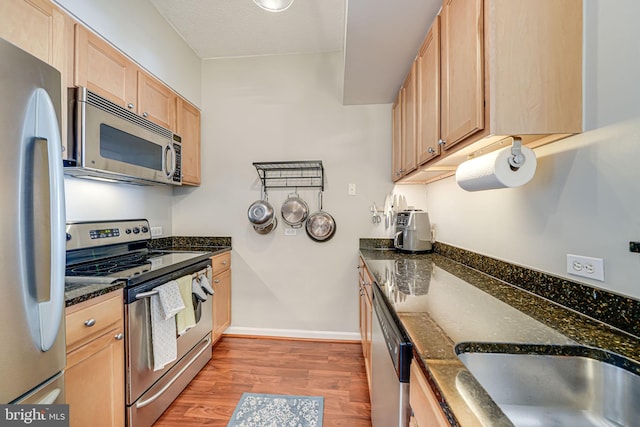 880 N Pollard St Unit 1021, Arlington, VA 22203 - kitchen featuring appliances with stainless steel finishes, light wood-type flooring, light brown cabinetry, dark stone countertops, and baseboards