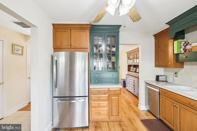 9 Stratton Ct, Robbinsville, NJ 08691 - kitchen with a ceiling fan, light countertops, glass insert cabinets, stainless steel appliances, and light wood-style flooring