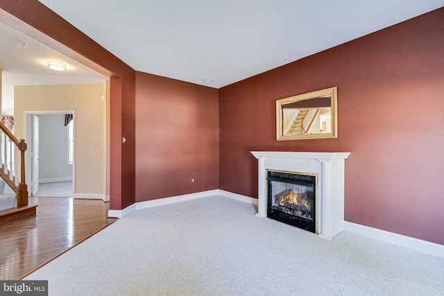 1005 Chaff Way, La Plata, MD 20646 - unfurnished living room featuring a glass covered fireplace, stairs, carpet, baseboards, and wood finished floors